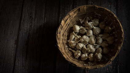 garlic in basket on dark wooden table.