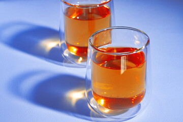 Two glass cups of tea on blue background