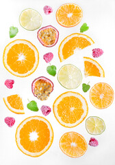 Fruit backdrop. Slices of orange, tangerine and lime, passion fruit, raspberry and mint leaf are flying against the white background. Levitation. Juicy mix