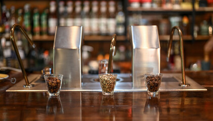 The coffee beans in the glass cup with blerred background modern coffee machine in cafe.