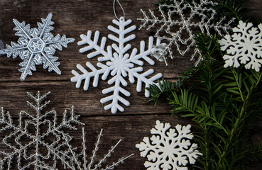 various snowflake ornaments on wooden ground with yew branch in cold colours outside