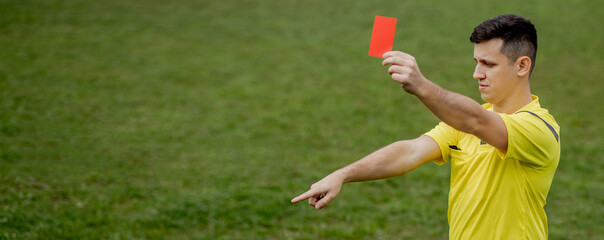 Angry football referee showing a red card and pointing with his hand on penalty