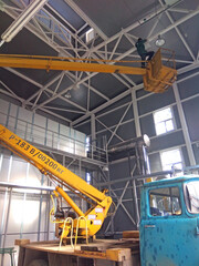 Scissor lift platform with hydraulic system elevated towards a factory roof with construction workers, Mobile aerial work platform