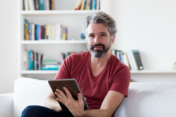 German mature adult man reading news and e-book at tablet computer