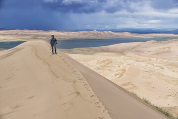 Fototapeta na wymiar Tourist Walking Along the Edge of the Sand Dune.