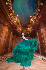 Portrait of a beautiful young girl in a Haute couture green dress dancing in a luxurious palace...