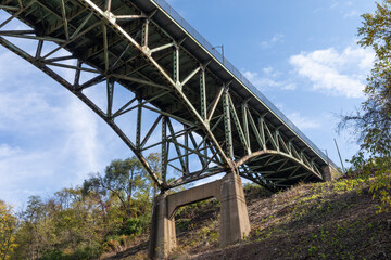 Hillside with concrete supports of an overhead arch bridge, fall season with blue sky, horizontal aspect