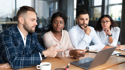 Serious Coworkers Discussing Project During Corporate Meeting In Modern Office
