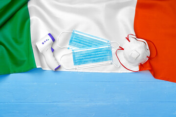 Medical mask and contactless thermometer on flag of Italy