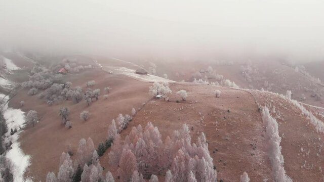 Aerial view of wintertime scene in the Transylvanian village, Pestera, with white frost, fresh snow, blizzard, and fog, at the foot of the Carpathian Mountains