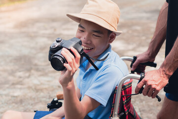 Fototapeta premium Disabled child on wheelchair is smiling,playing,learning in the outdoor park activity like other people,Lifestyle of special child, Life in the education age of children, Happy disability kid concept.