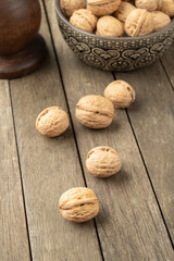 Walnuts over a wooden table and into a bowl
