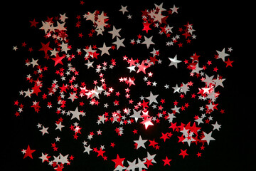 Bright red and white stars confetti on black background. Holidays concept.