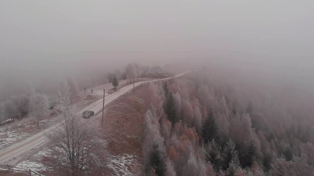 Aerial view of wintertime scene in the Transylvanian village, Pestera, with white frost, fresh snow, blizzard, and fog, at the foot of the Carpathian Mountains