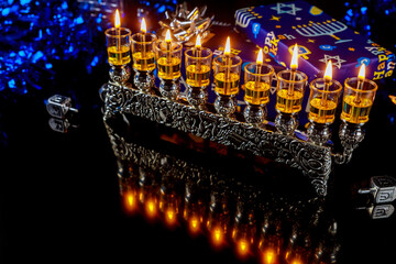 Menorah with oil candles and reflection on surface for Hanukkah jewish holiday.