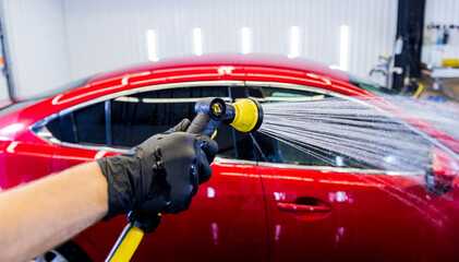 Service worker washing car on a car wash.
