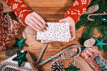 Female hands opening christmas gift above wooden table. Top view