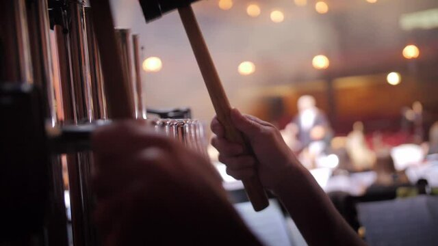 Hands with hammers play the musician bar chimes.