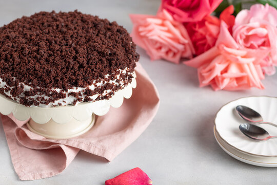 delicious chocolate cake with cream on gray background with bouquet of roses. Women's Day, Valentine's Day. horizontal image