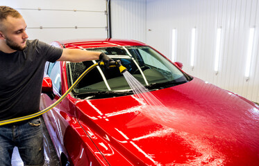 Service worker washing car on a car wash.