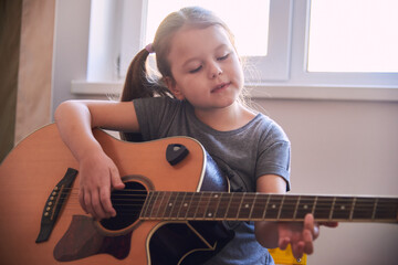 a little girl learns to play the guitar from notes. Music school for children.Musical notation.