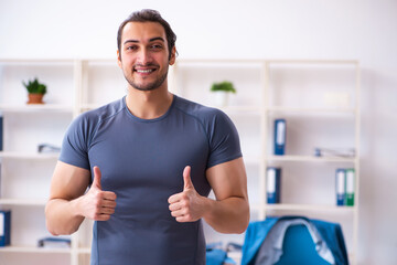 Young handsome employee doing sport exercises in the office