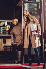 a cheerful young woman, with a present, entering a bar and looking for her boyfriend