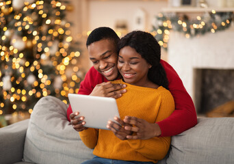 Family happy millennial african american husband and wife look at tablet and congratulate friends