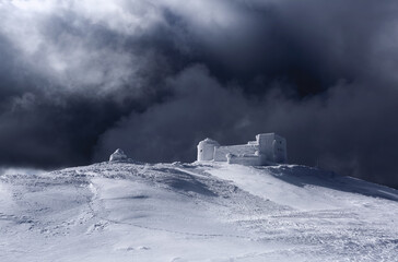 The old observatory covered with textured snow. Dramatic stormy sky with gray clouds. Winter...