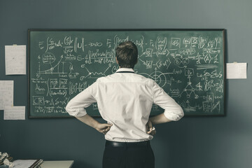 Mathematician solving problems and writing formulas on the chalkboard