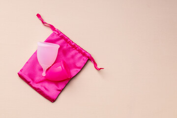 Two menstrual cups on beige background top view