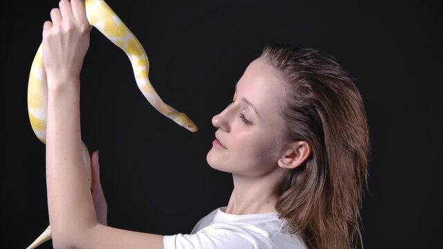 Slow motion video of albino python kissing blond woman