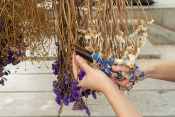 close up hand of woman using scissors to cut dry flowers to decorate artwork