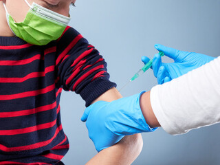 Boy being vaccinated by a nurse, isolated on gray