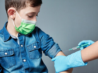 7 year old boy being vaccinated by a nurse or doctor, vaccination concept