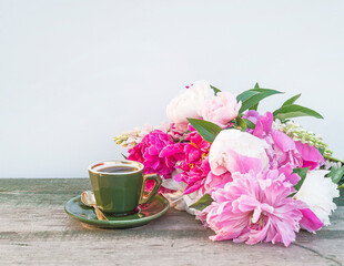 Vintage cup of coffee and bouquet of puprle peonies on wooden table annd white background