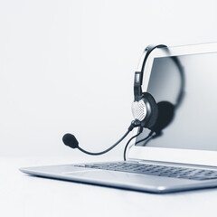 Laptop. Mockup screen and headphones on grey desk and plain background. Distant learning or working from home, online courses or support minimal concept. Helpdesk or call center headset