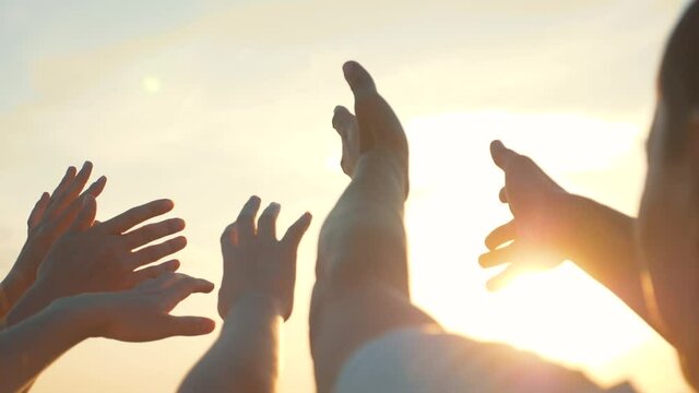 People hands reach out to the sun and god at sunset. Happy family together hands up religion. Teamwork. Prayer for help. People turn to God together in prayer. People in religion. Helping hand sun
