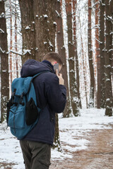 Fototapeta na wymiar A man walks on a forest path in winter and talks on the phone. It snowed.