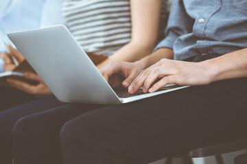 Naklejka premium Group of casual dressed business people working at meeting or conference, close-up of hands. Businessman using laptop computer. Teamwork or coaching concept