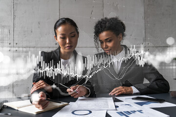 Two businesswomen work together in modern office on new project. Double exposure. Concept of success. Forex stock market graph.