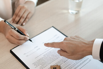 The apartment landlord is pointing to the contract to keep tenants sign on paperwork.