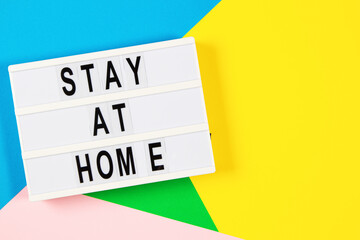 Lightbox with text STAY AT HOME on yellow, green, pink and light blue background. Top view