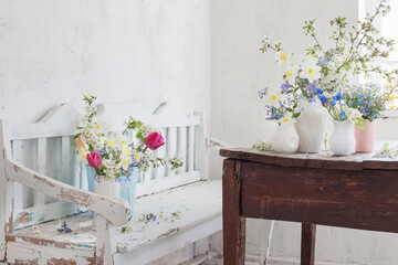 spring flowers in vintage white interior with old wooden bench