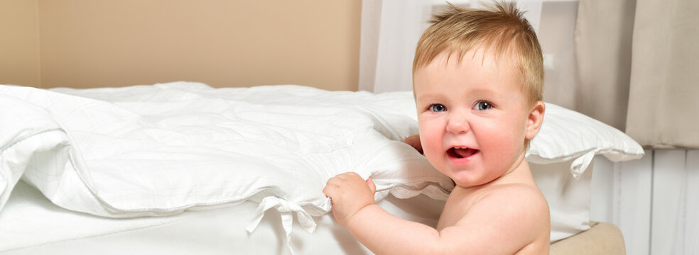 Happy cheerful baby in the interior of the bedroom. Laughter.