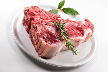 Raw T-bone steak with bay leaf and rosemary