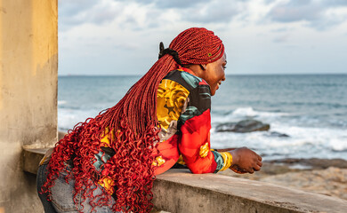 African woman with beautiful red rasta hair looking out over the sea from a balcony in Accra Ghana...