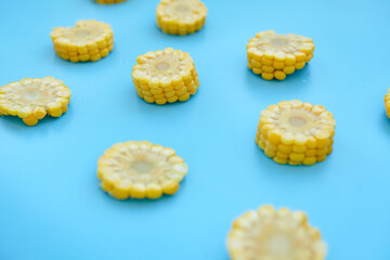 Sweetcorn Against Blue Background. Flat lay composition with tasty sweet corn cobs on color background. Cobs of ripe raw corn on blue background. Top view.