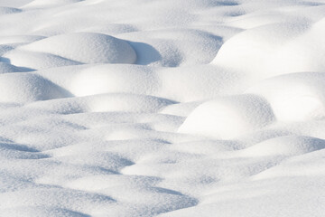 Smooth snow drifts on sunny winter day. Deep and high snow drifts illuminated by sunlight and being in shadow