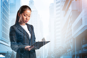Attractive young Asian business woman in suit taking notes into the notebook, new career...